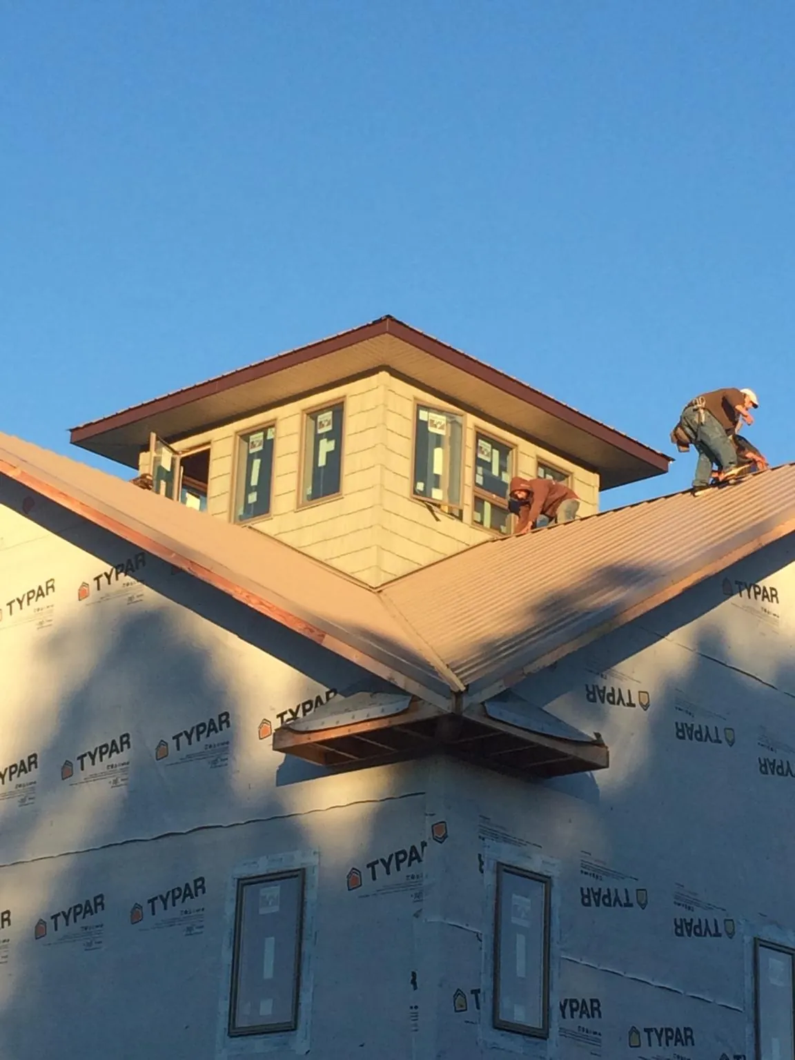 Roofers working around a rooftop cupola on a new metal roof at sunset — Roof Waterproofing in Frederick by Roofing Brothers